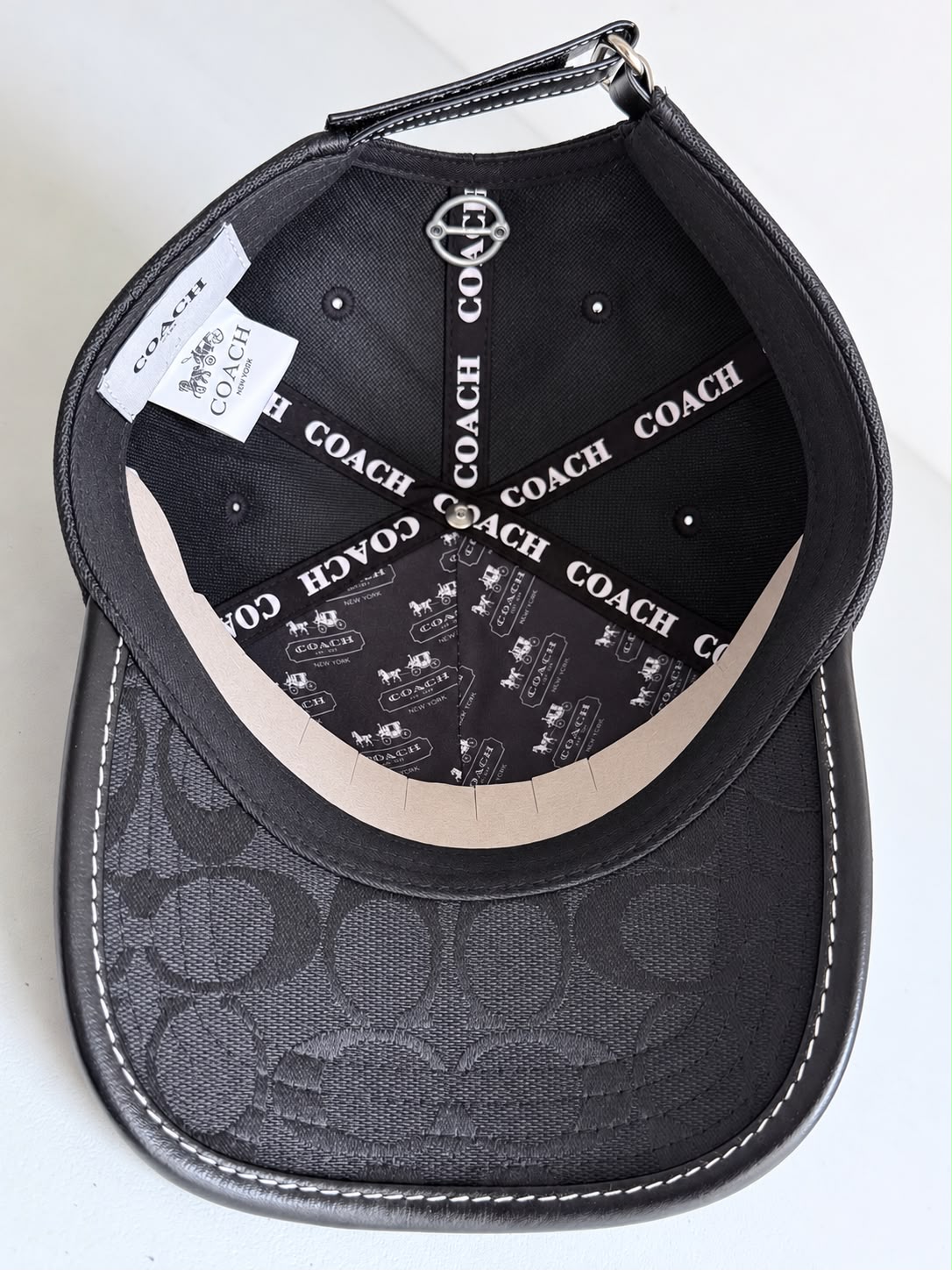 Gorra Coach negra con monograma y logo C metálico, vista frontal