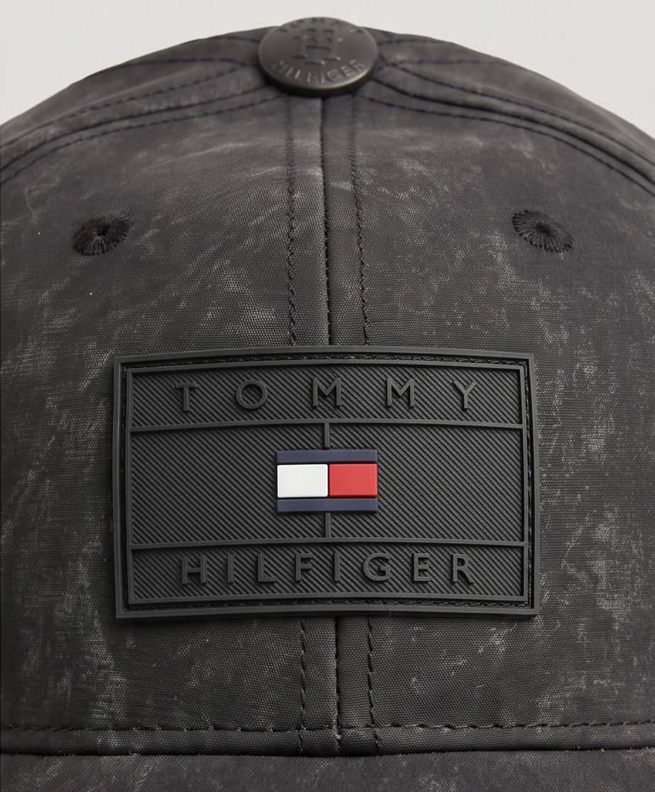 Gorra Tommy Hilfiger Waxed Monogram detalle parche PVC close-up