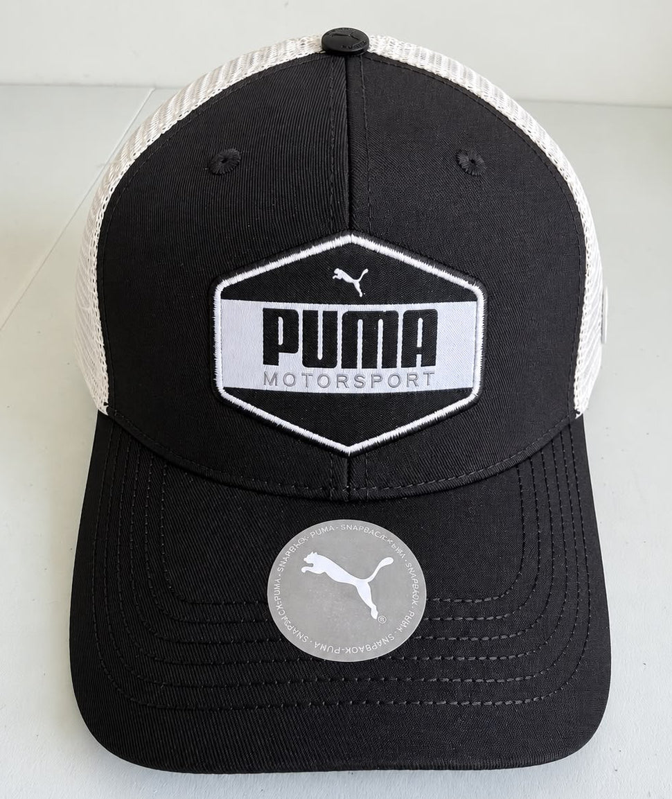 Vista lateral de gorra Puma Motorsport negra con paneles traseros de malla blanca y logo Puma