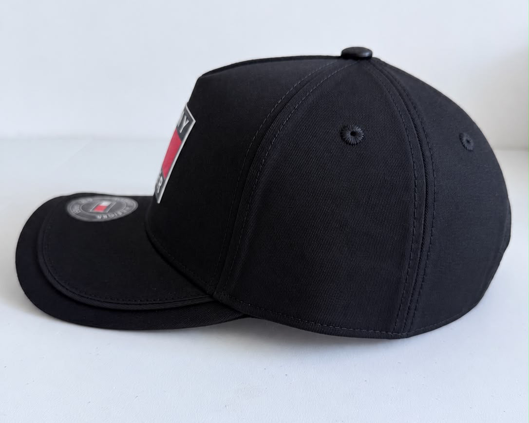 Parte trasera de gorra Tommy Hilfiger negra con emblema circular y cierre metálico ajustable