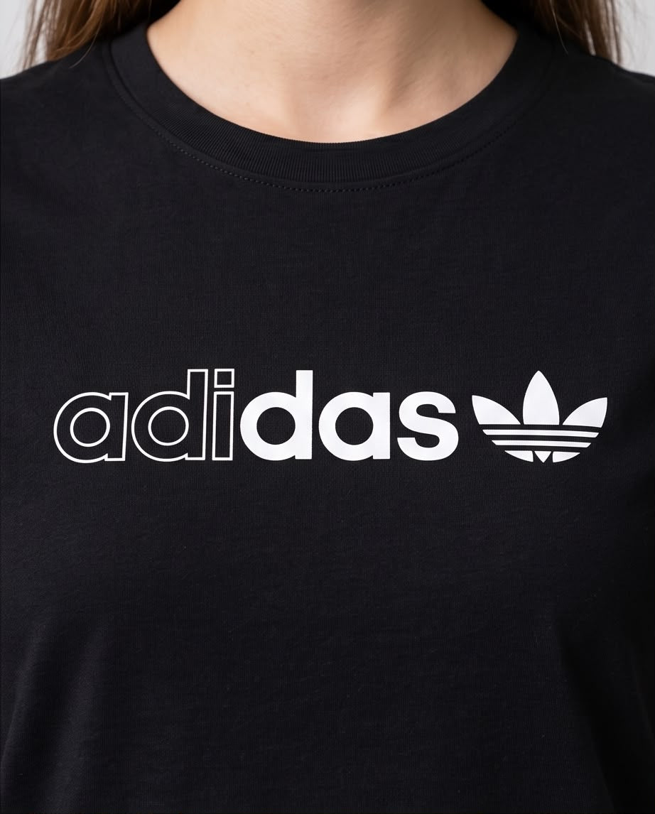 Camiseta negra adidas Trefoil blanco para mujer, modelo sentada
