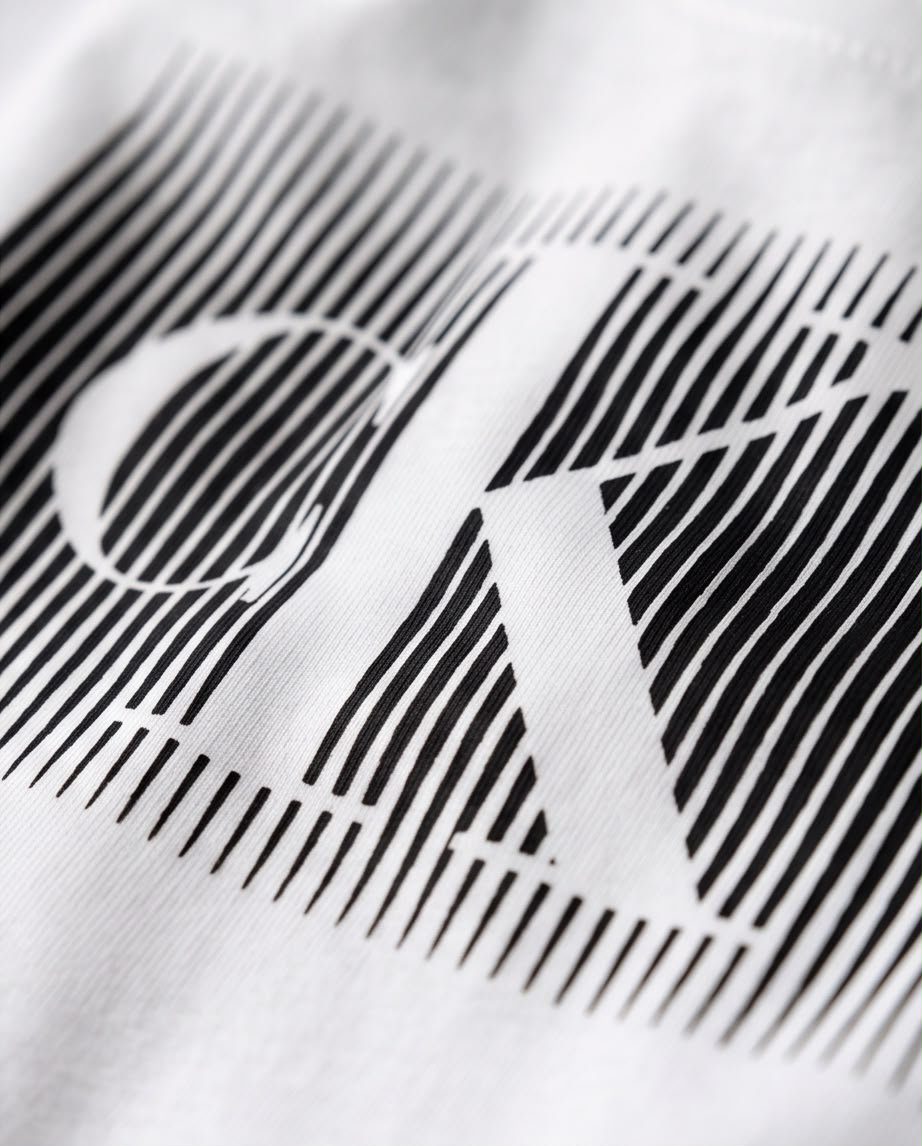 Detalle del estampado CK de líneas negras sobre camiseta blanca