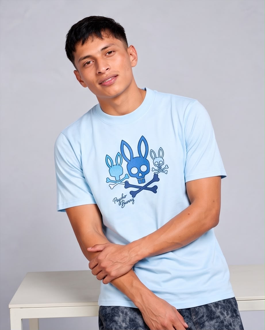 Camiseta azul claro con tres conejos azules, modelo apoyado en mesa