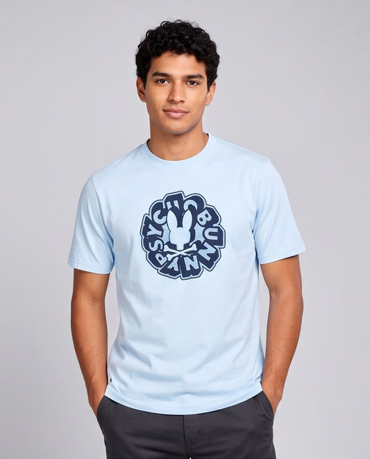 Camiseta azul claro con letras circulares y conejo central, modelo con manos en bolsillos