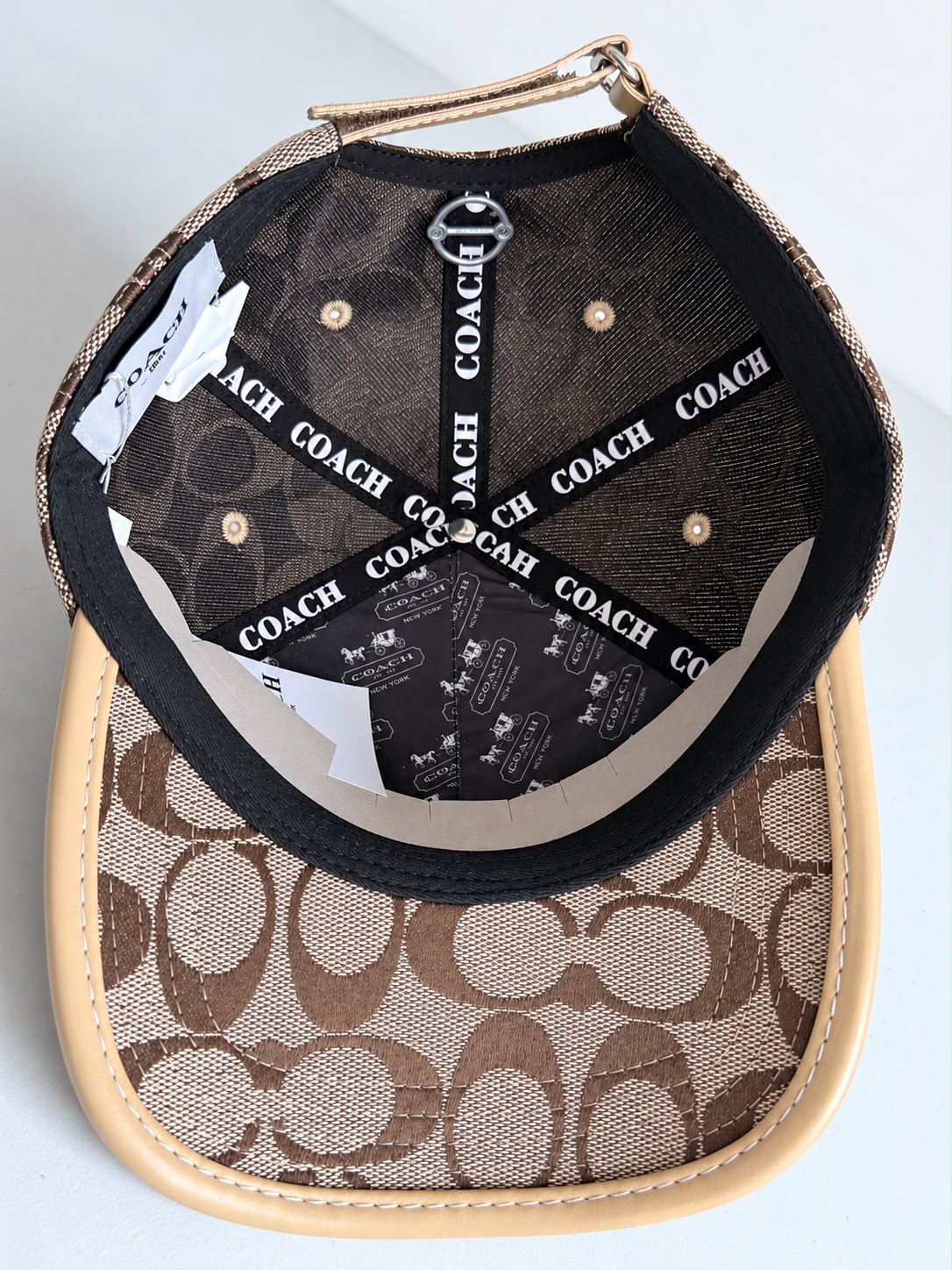 Gorra Coach monograma beige con café y logo metálico, vista frontal