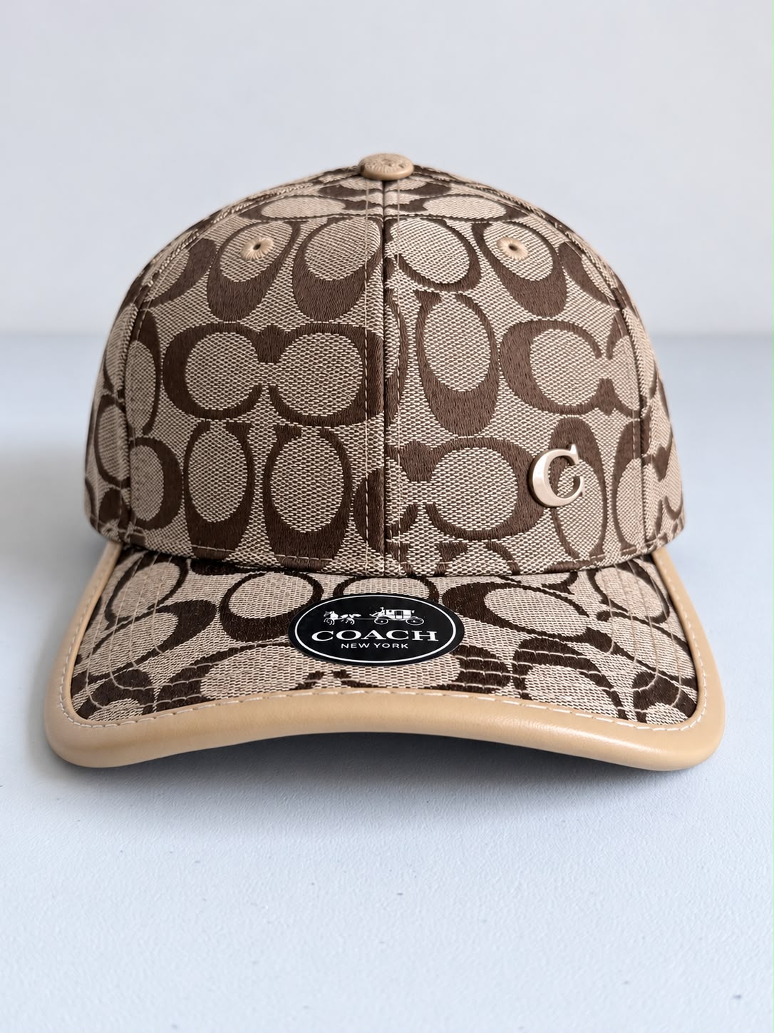 Detalle del monograma café sobre beige y logo C metálico