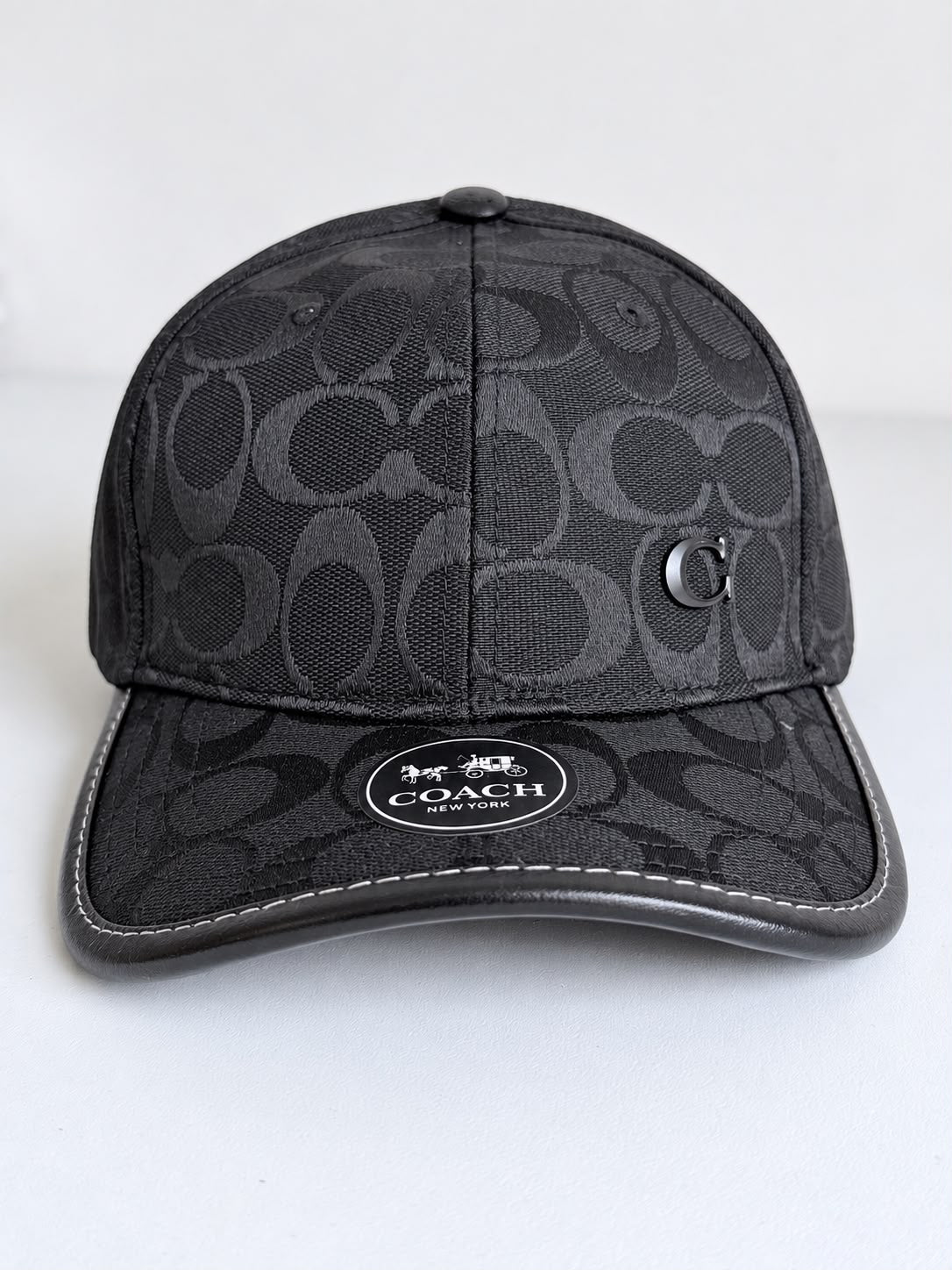 Detalle del monograma negro y gris carbón y logo C metálico